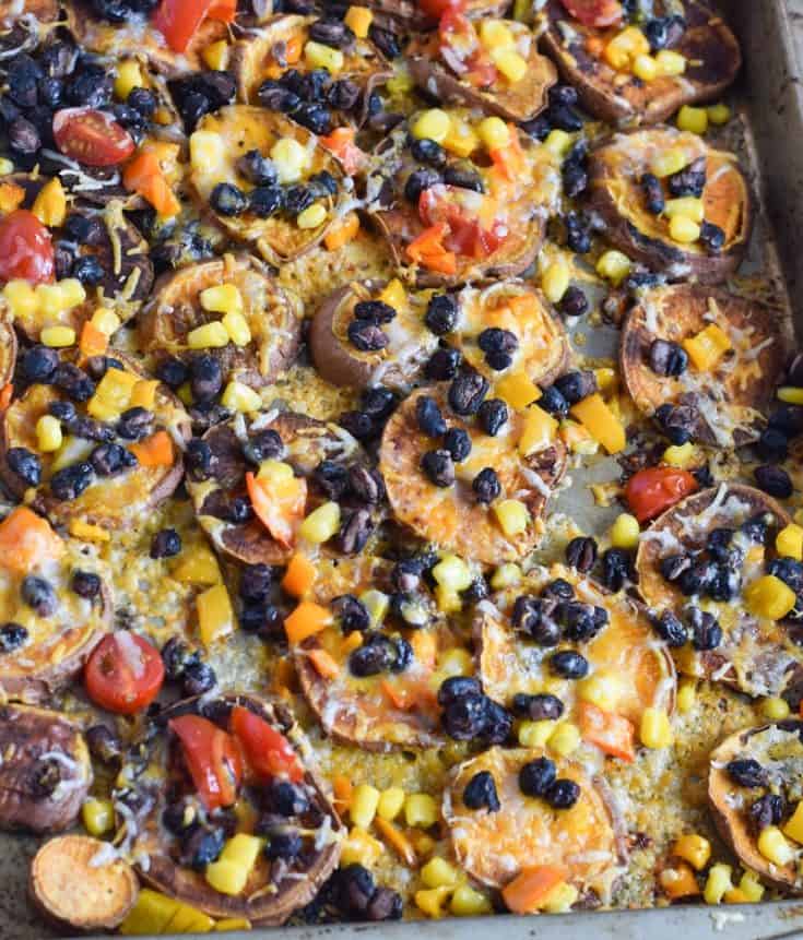 closeup of sweet potato nachos on sheet pan topped with black beans, corn and cheese| Bucket List Tummy