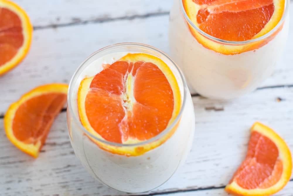 mango smoothie with greek yogurt and orange on top in clear glass