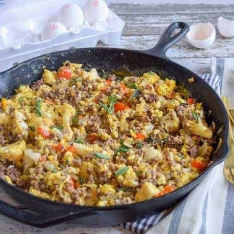 skillet with eggs, ground beef and vegetables on striped napkin