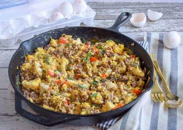 skillet with eggs, ground beef and vegetables on striped napkin