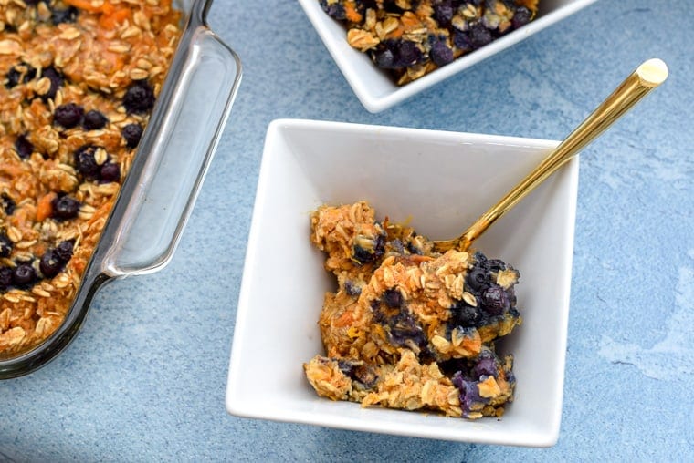 sweet potato oatmeal with blueberries in white serving bowl with a spoon