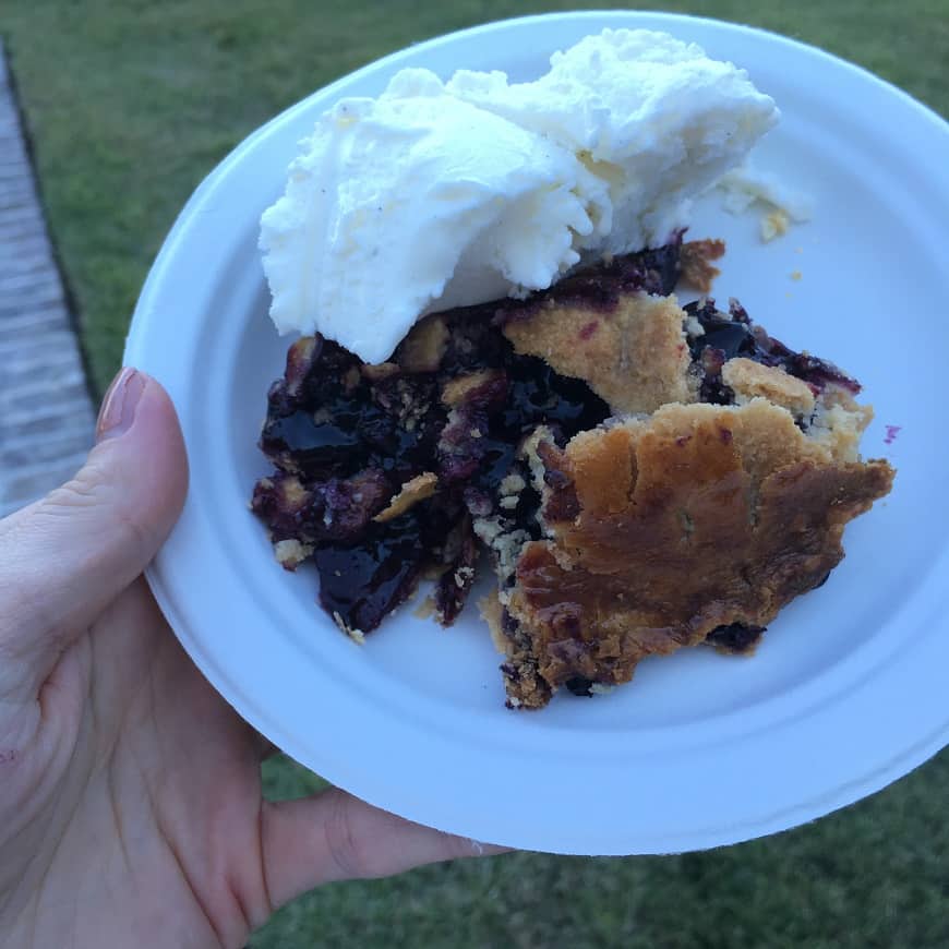 white plate with piece of blueberry pie and ice cream 