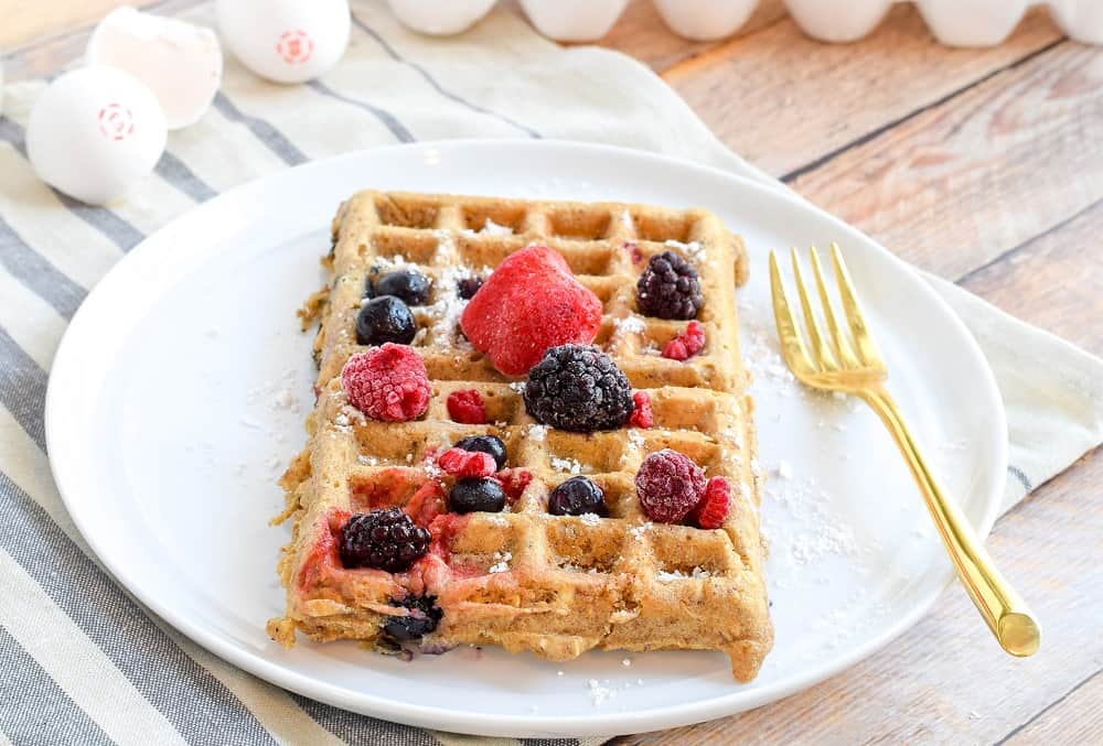 belgian waffles topped with frozen berries on white plate