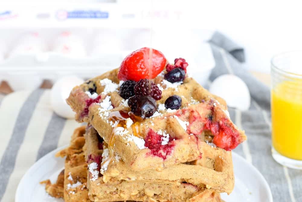 banana oatmeal waffles in stack, topped with fruit and maple syrup