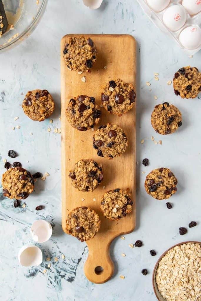 Serving board with chocolate chip cherry oatmeal muffins and scattered Chocolate Chips