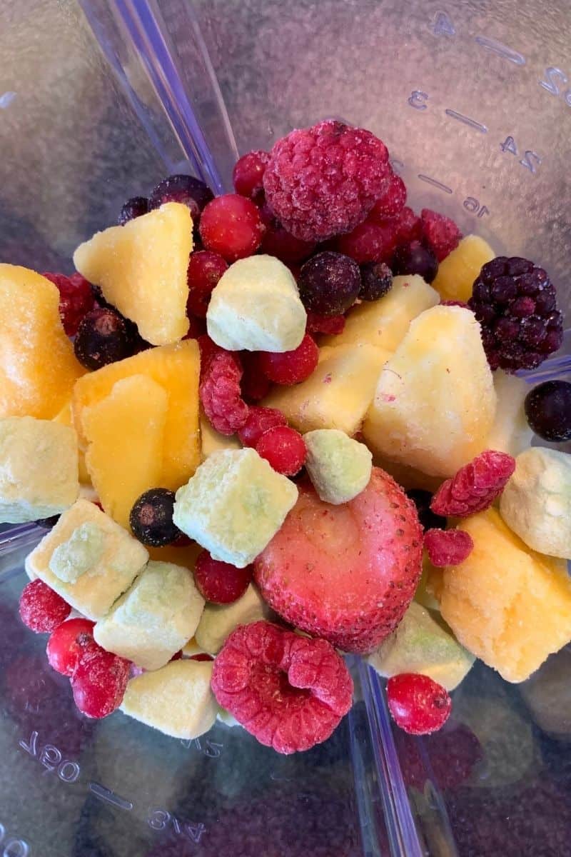 variety of frozen fruit in empty blender