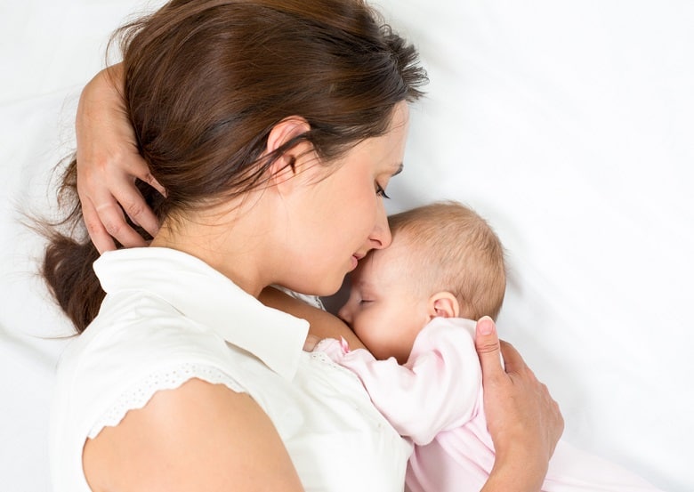 Mother breastfeeding child in bed