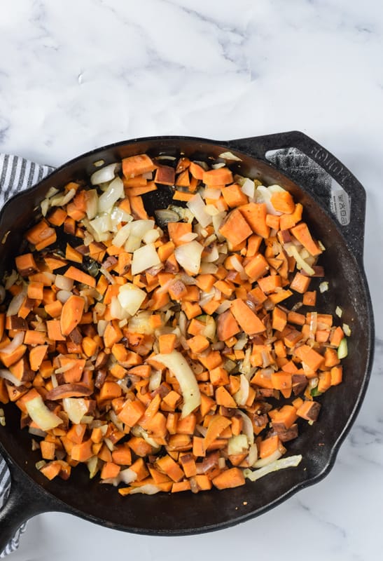 diced sweet potatoes and onions in cast iron skillet