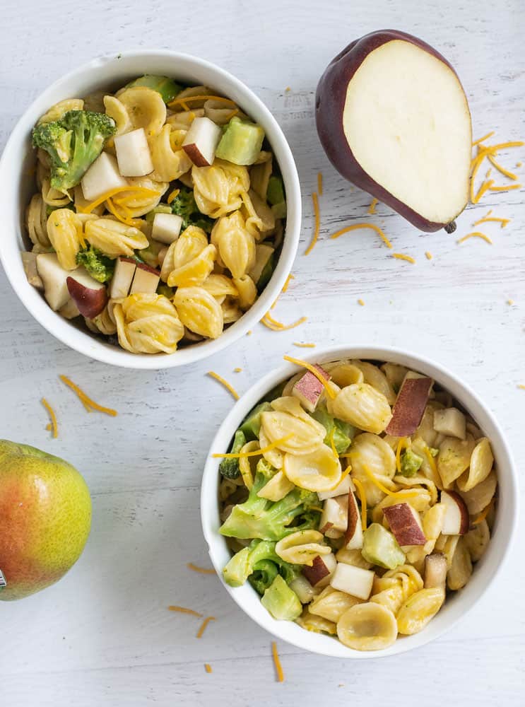 mac and cheese with pears and broccoli in two white bowls on white counter
