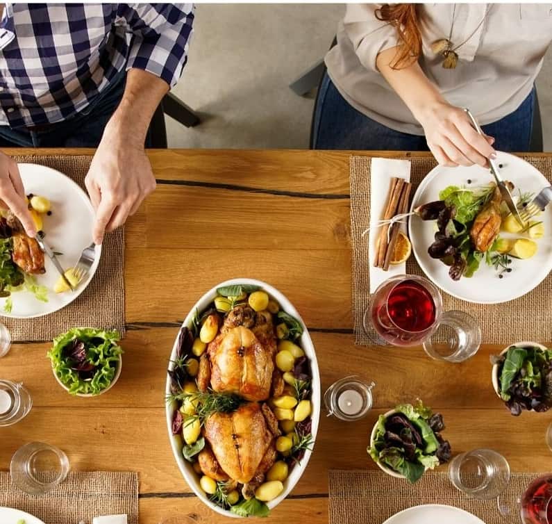 table with various thanksgiving plates and sides that people are enjoying together