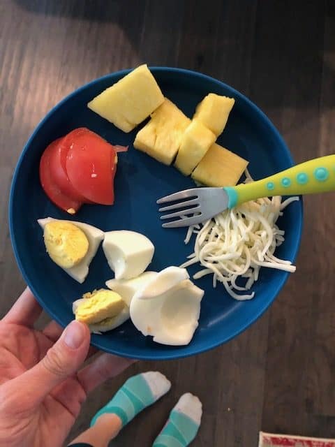 blue toddler plate with pineapple, tomato, hard boiled egg and shredded cheese