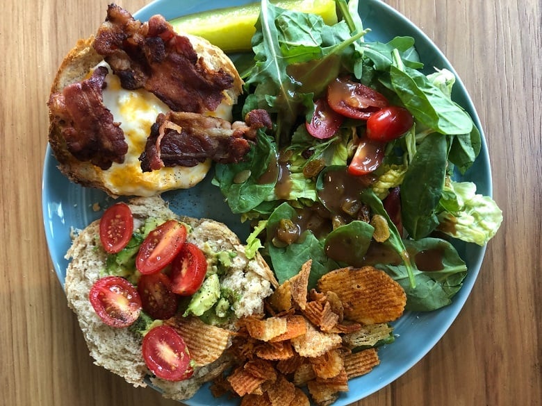 blue plate with bacon and cheese and a salad with chips