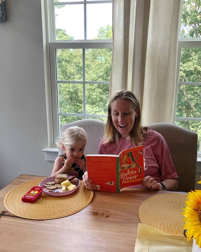 mom reading book to daughter during snack time