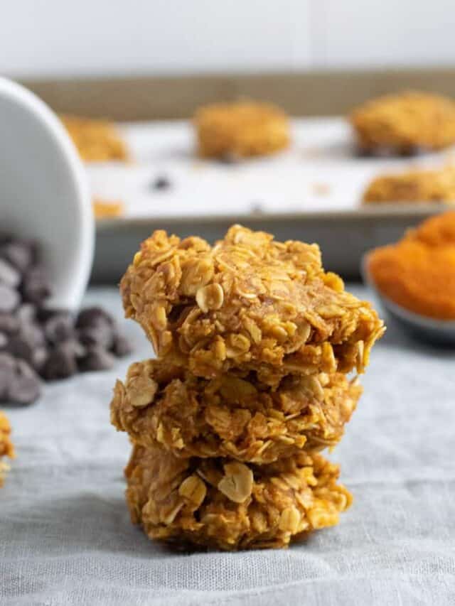 stack of 3 pumpkin no bake cookies with chocolate chips in background
