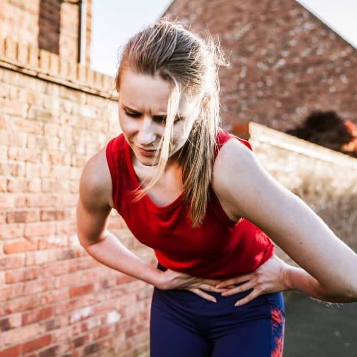 girl in red shirt bending over with stomach pain after running