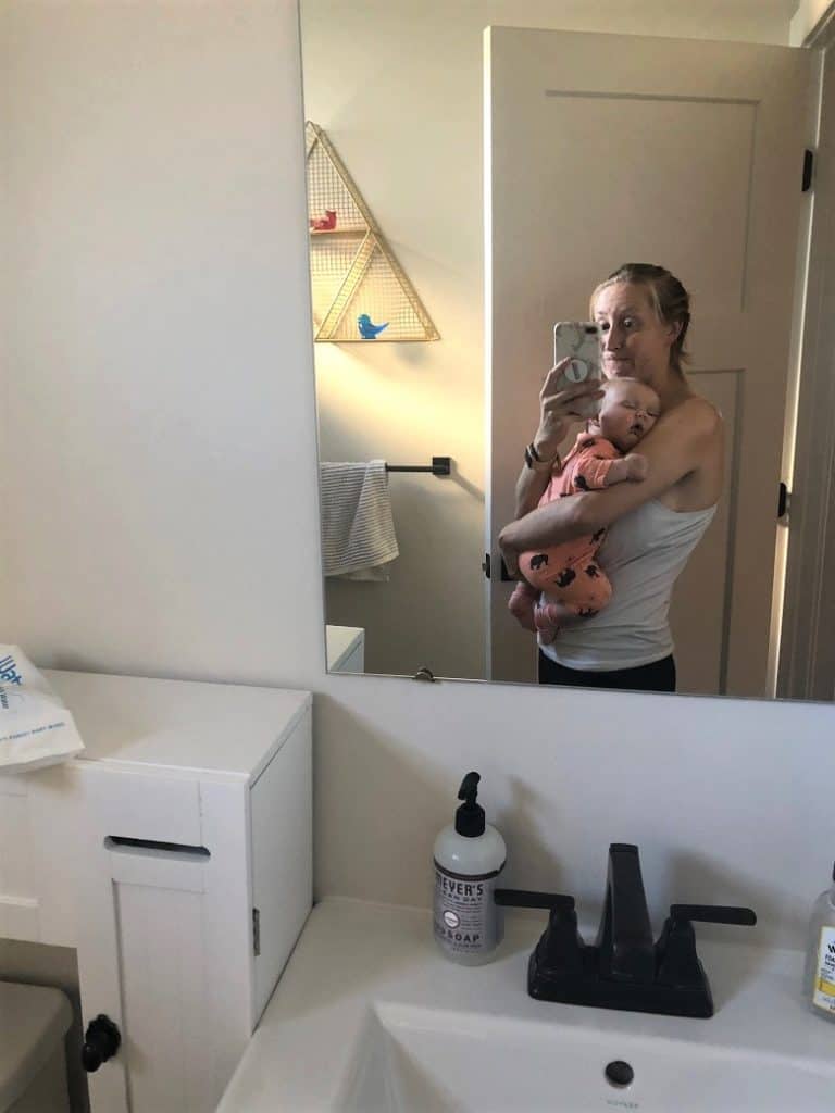 holding a sleeping baby and looking in mirror