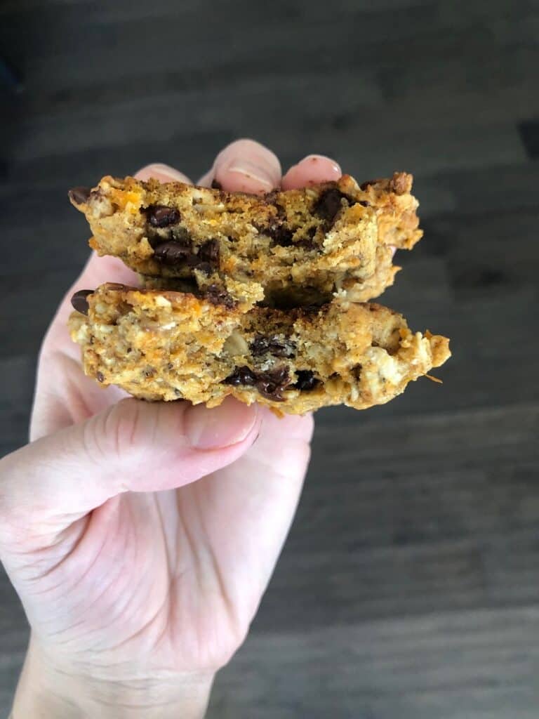 holding two freshly baked vegan breakfast cookies with chocolate chips