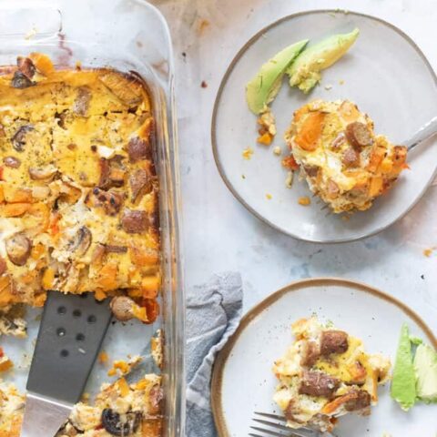 overhead photo of two plates with piece of breakfast casserole and avocado slices and baking dish with turkey sausage casserole