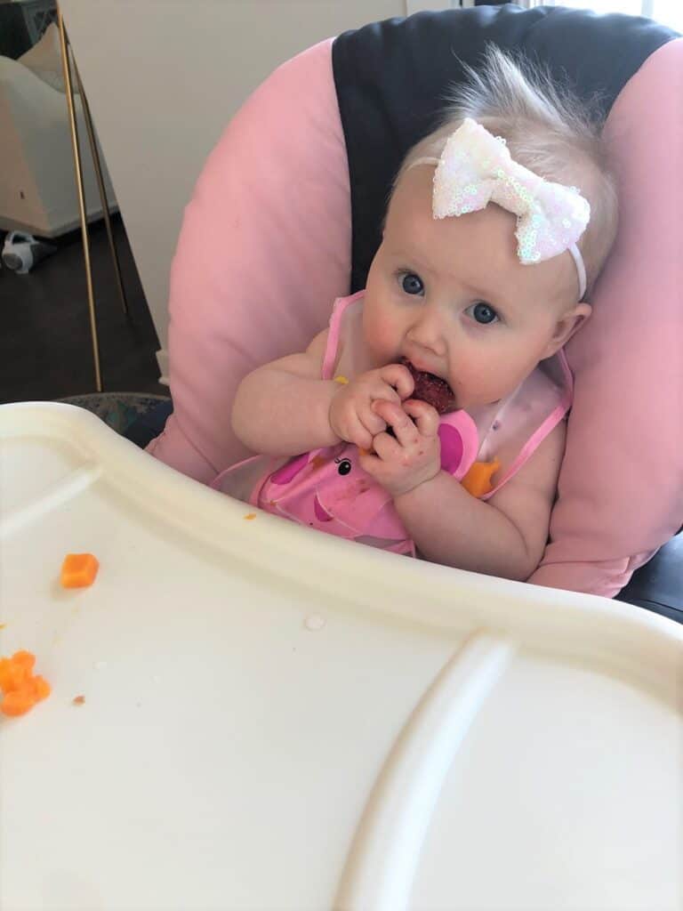 baby eating strawberry in high chair