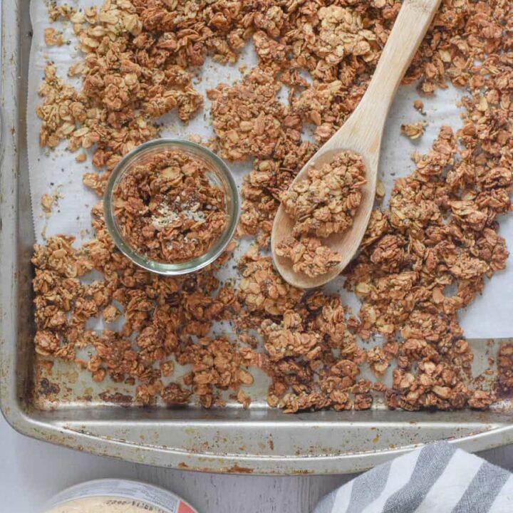 overhead view of baking sheet with protein granola spread out and wooden spoon with granola on it