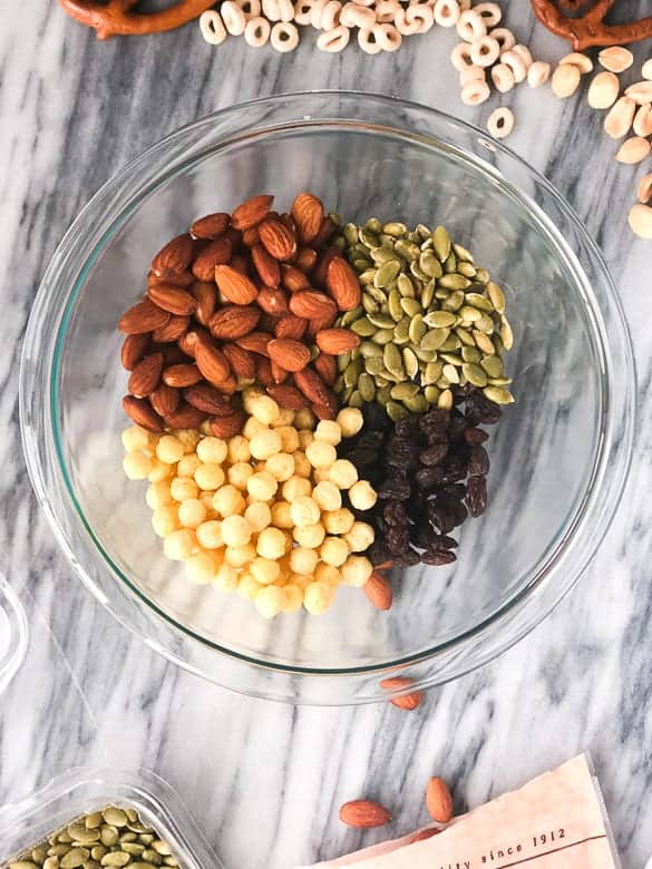 clear bowl with kix, almonds, pumpkin seeds and raisins