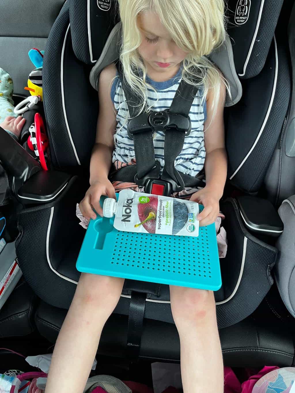 kid in car seat holding snack