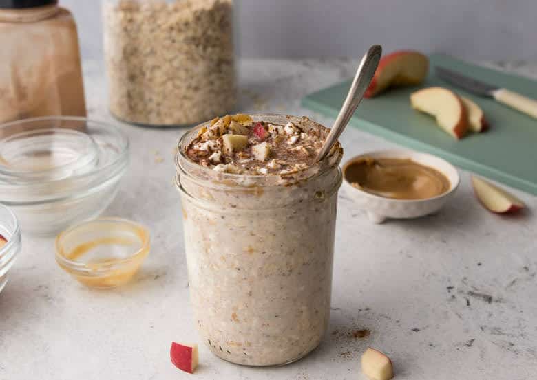 mason jar with oats, cottage cheese, hemp seeds and cinnamon with spoon mixed in