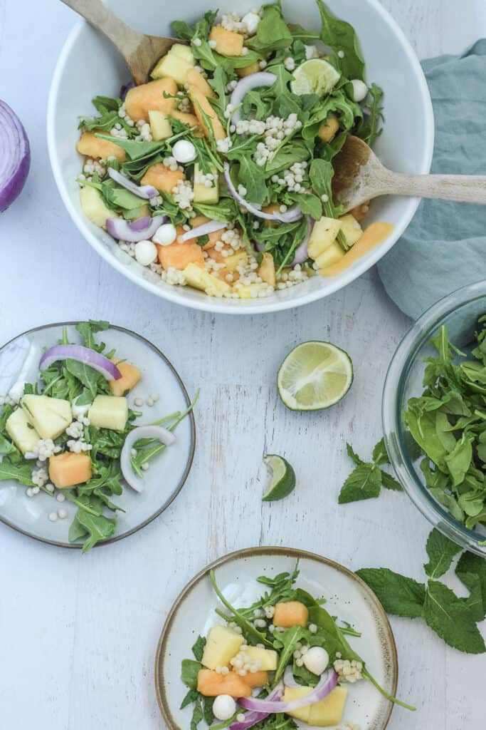 mint cantaloupe salad with mint and pineapple in white serving bowl