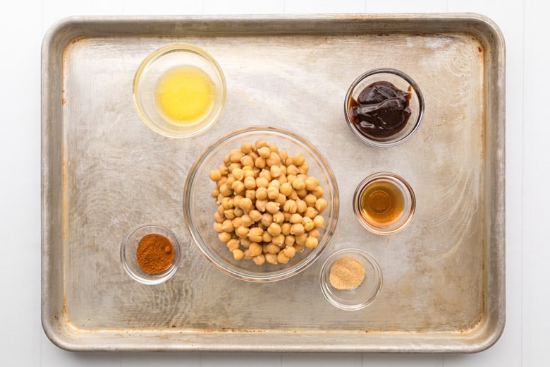 Bowls with chickpeas and sauces on baking pan