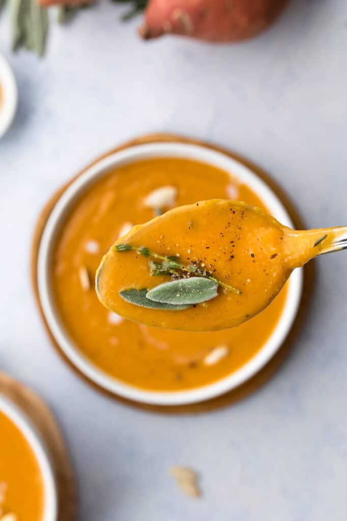 spoon with pumpkin sweet potato soup and a sage leave on it