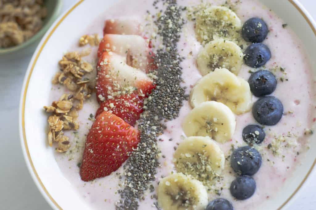 strawberry banana smoothie bowl closeup with fruit, chia seeds and granola