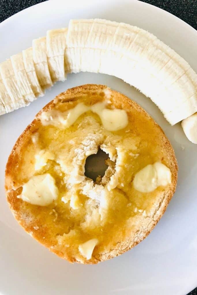 bagel with butter and banana on white plate