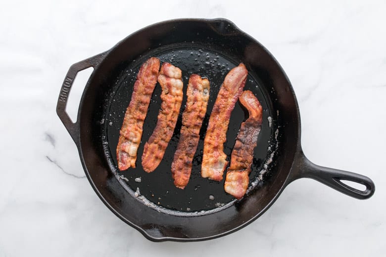 bacon cooking on cast iron skillet