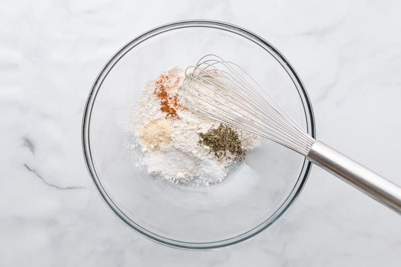 mixing flour and dry ingredients in a bowl with a whisk