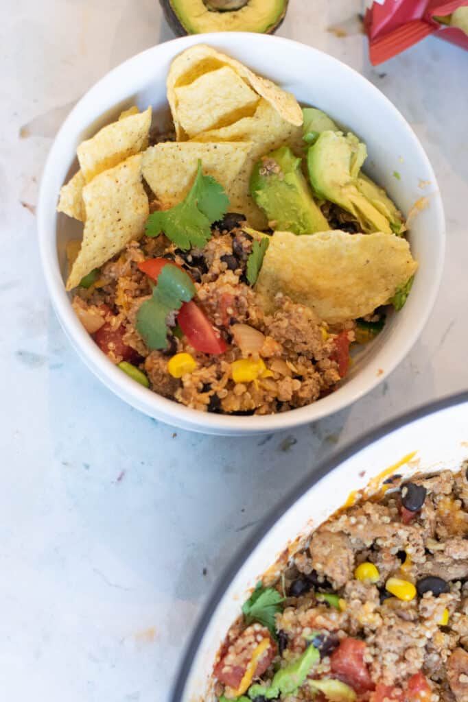 ground turkey and quinoa in white bowl with tortilla chips and avocado on top