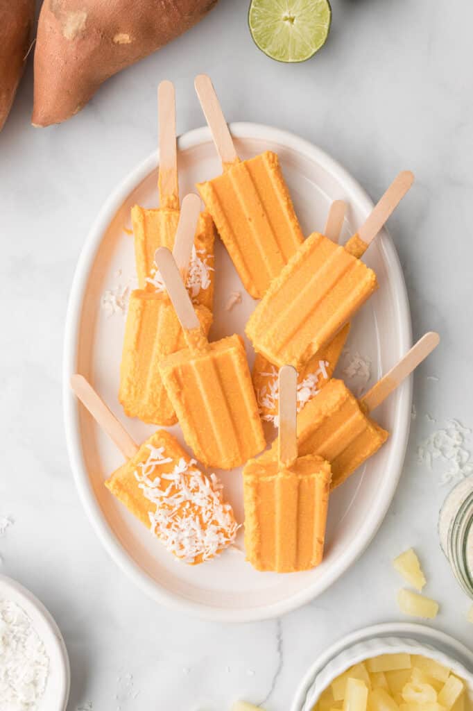 creamy coconut popsicles on sticks in white bowl