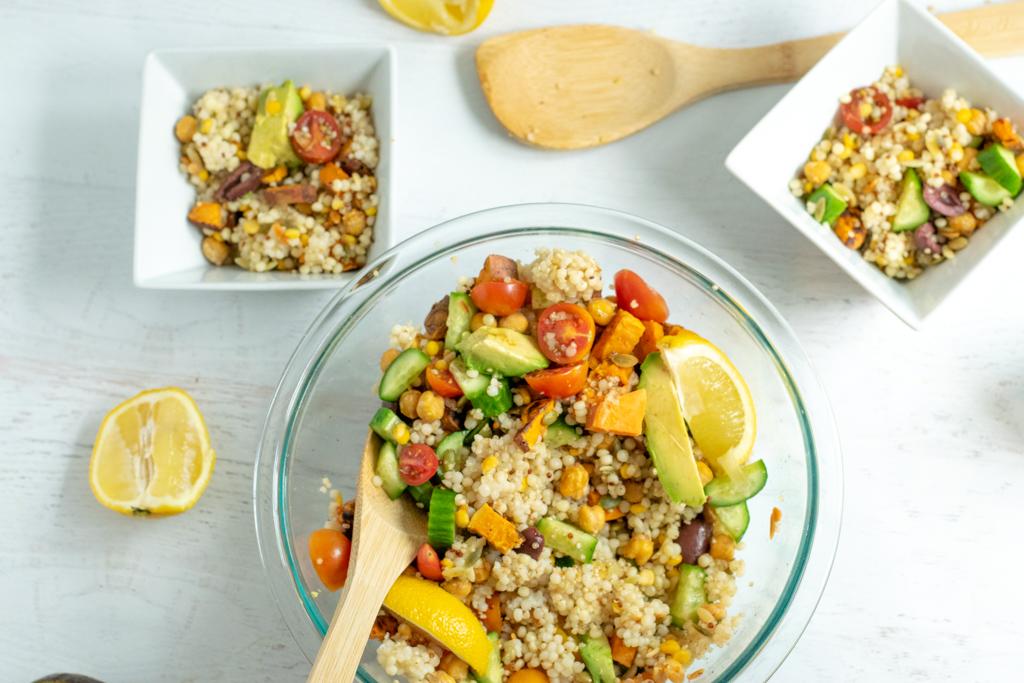 vegan couscous salad recipe in clear bowl with wooden serving spoon