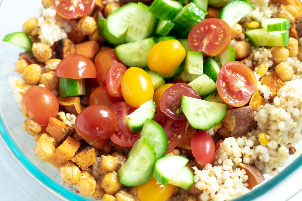 vegan pearl couscous recipe topped with tomatoes, cucumbers and roasted chickpeas