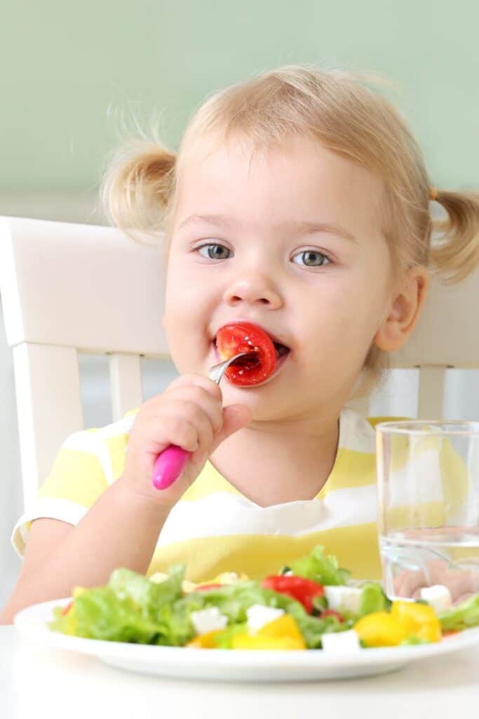 toddler eating plate of veggies