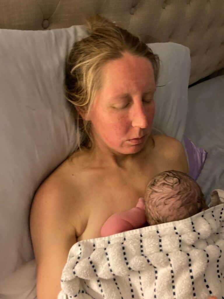 woman in bed holding newborn after home birth