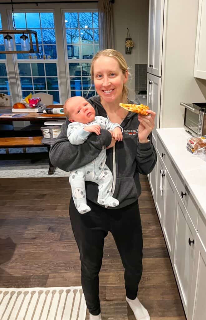 mom holding baby eating pizza