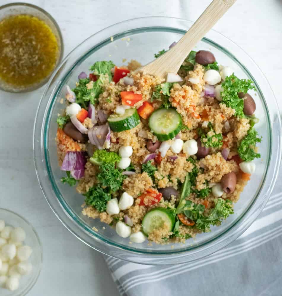 Quinoa salad with vegetables in bowl with serving spoons