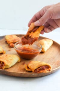 Pizza bites made in the air fryer dipping into pizza sauce