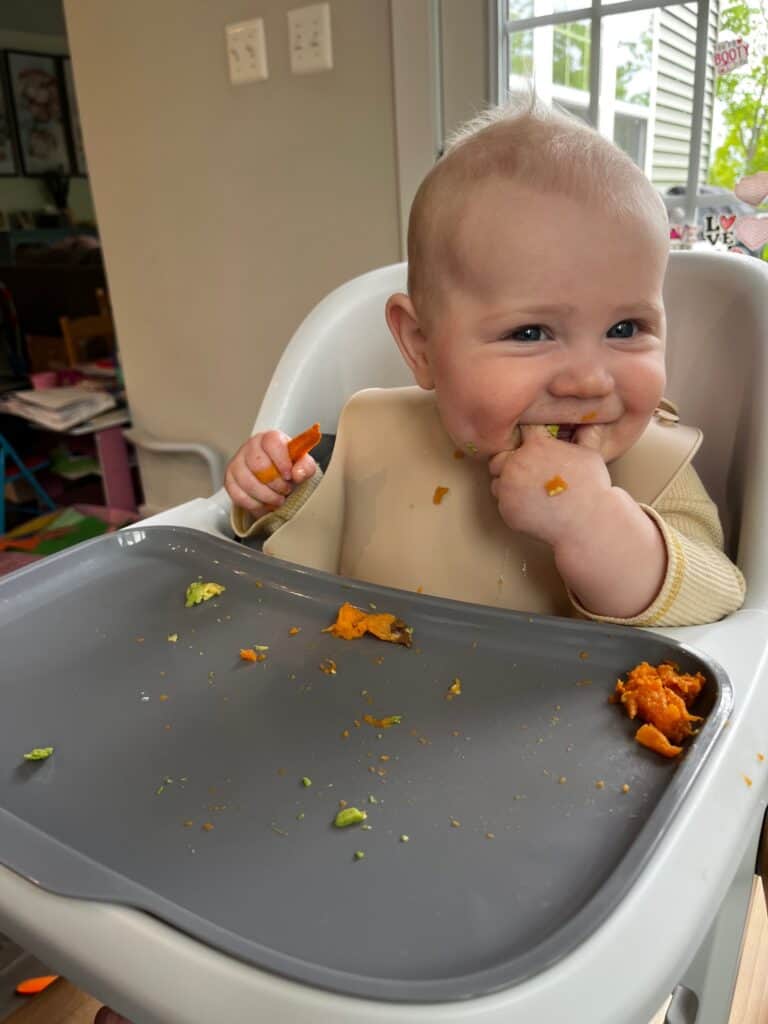 baby sitting at high chair with sweet potatoes for baby led weaning
