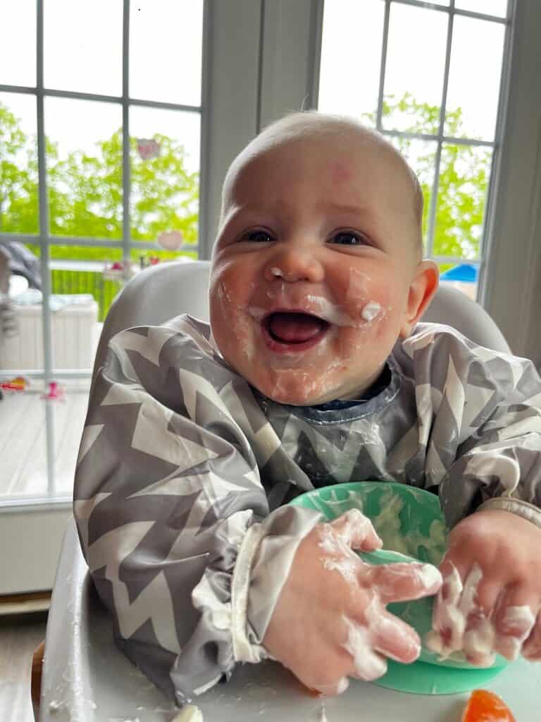 baby eating yogurt in high chair
