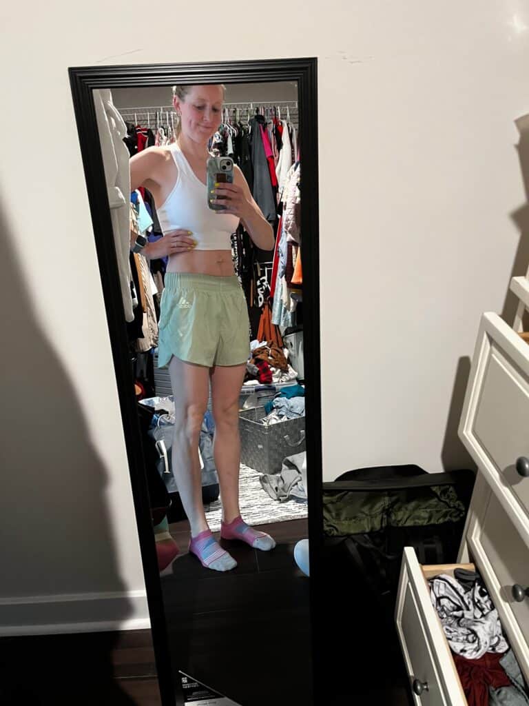 girl in mirror with white sports bra and green shorts