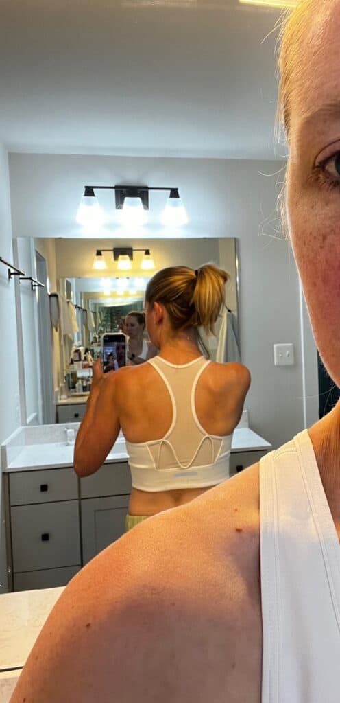 girl in mirror wearing white sports bra