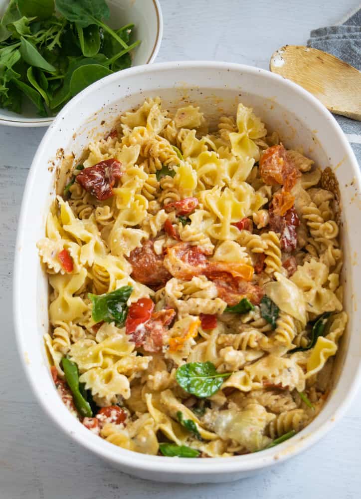 pasta with goat cheese and veggies in white casserole dish