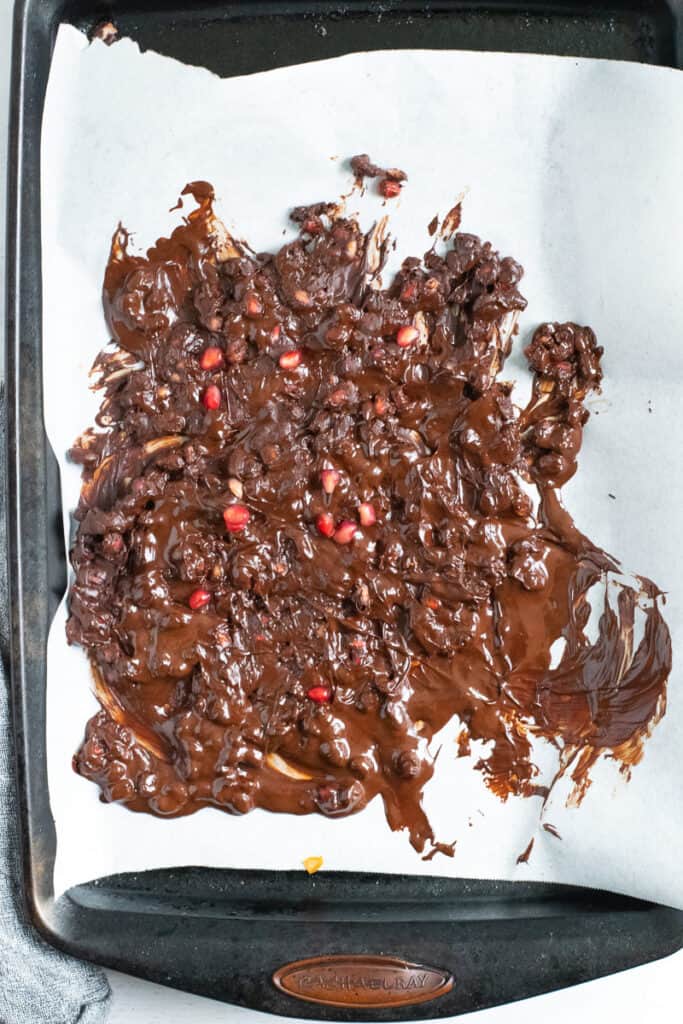 Baking sheet with parchment paper and dark chocolate melted pomegranate bark