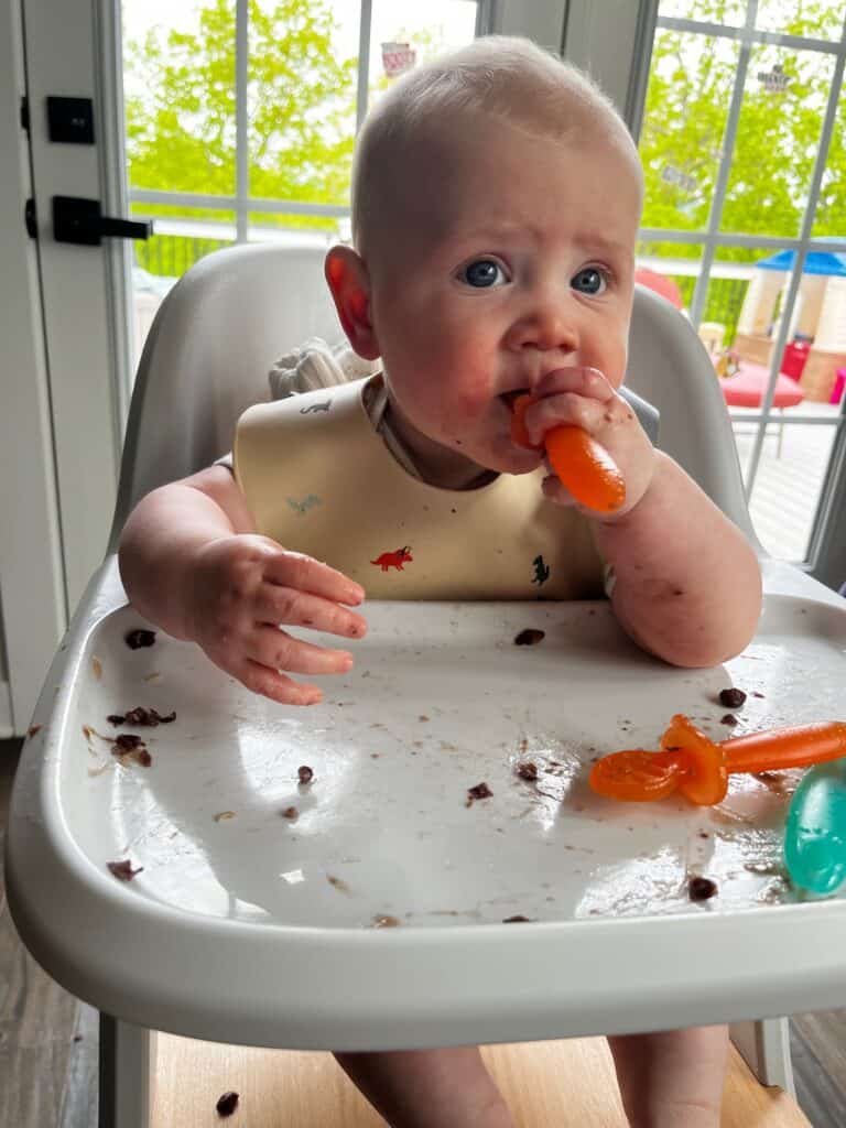 10 month old baby sitting in high chair eating